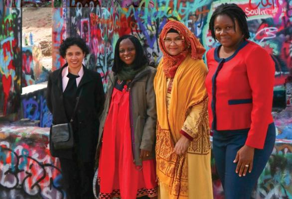 Women pose against a graffiti-ed wall