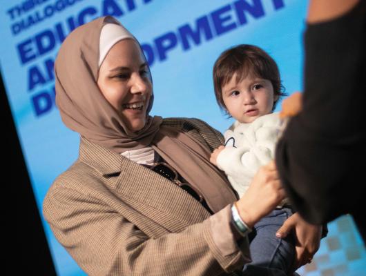 Woman holding baby to collect her OWSD pin