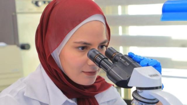 Woman scientist in headscarf looking through binoculars