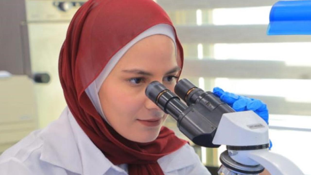 Woman scientist in headscarf looking through binoculars