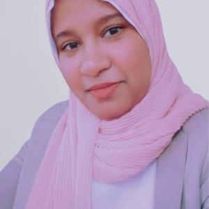 Formal personal photograph of a woman in professional attire and a pink hijab, looking directly at the camera, with a neutral background