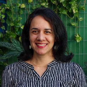 Forty&#039;s woman, with black hair and light skin. She is softly smiling.