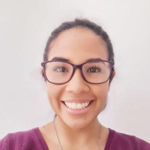 Women wearing glassses with a plum-colored shirt. She is smiling.  