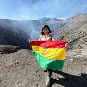 Bolivian geoscientist holding the Bolivian flag during a field expedition at Mount Bromo volcanic landscape, Indonesia.