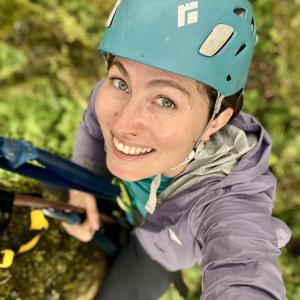 A smiling woman with a helmet on a tree 