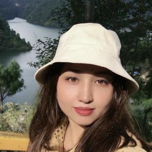 Portrait of Prabina Raut, a Nepali sustainability advocate, outdoors with a lake and forested hills in the background