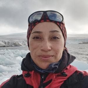 Women with antarctic outfit, on ice and ocean backgroung