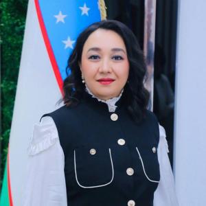 Professor Dildora Umarkhanova, Dean at Tashkent State University of Law, standing beside the flag of Uzbekistan