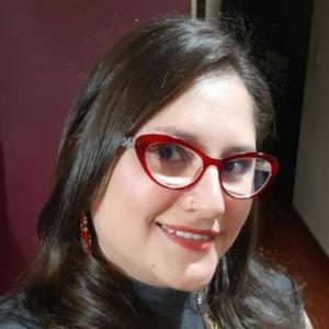 Photograph of scientist María Angélica Leal, astrobiologist. In the photo, she is wearing a gray shirt and red-framed glasses.