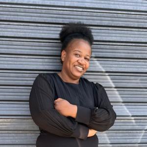 A lady wearing a black dress with tied natural hair afro
