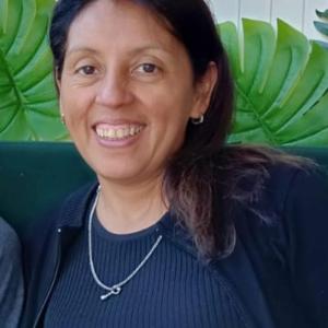 Fotografía profesional de Azucena Toro, miembro de OWSD, con fondo verde, vistiendo ropa formal y sonriendo