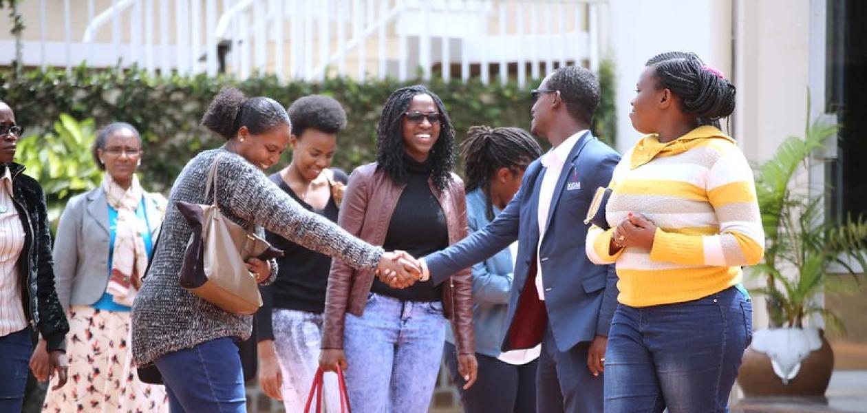 Women in a group, one shaking hands with a man